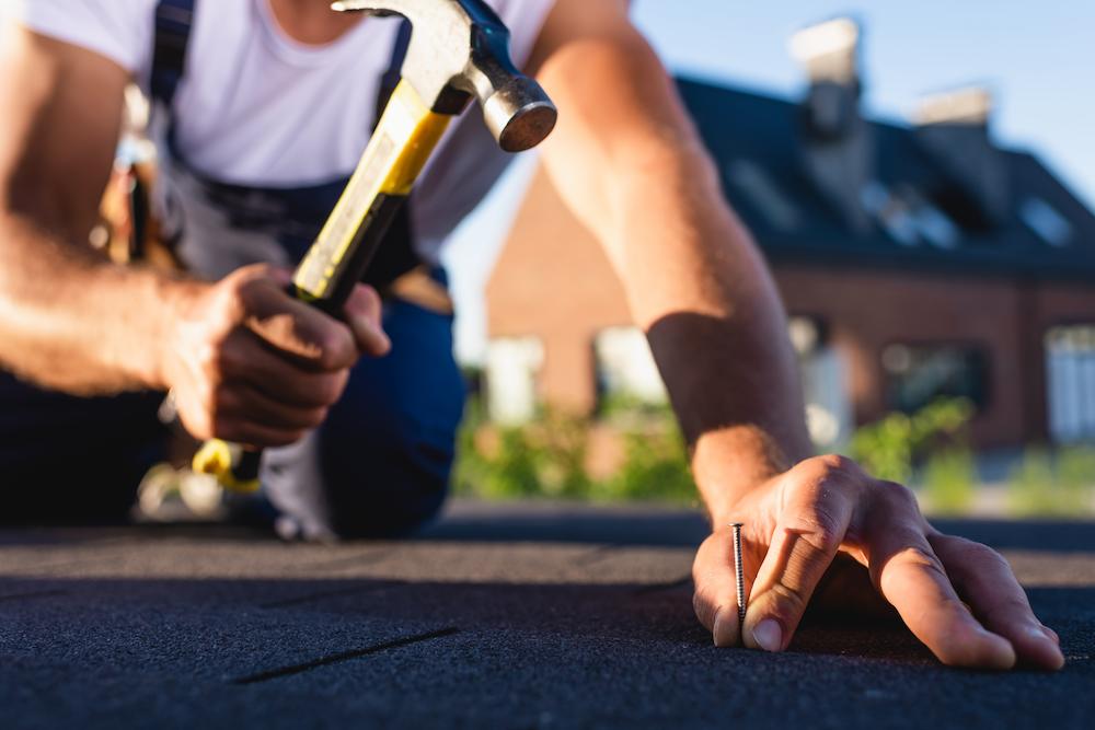 Protect your home or business with knowledgable Cicero Roofing Contractors from Beard Roofing & Exteriors image shows worker using hammer on roof