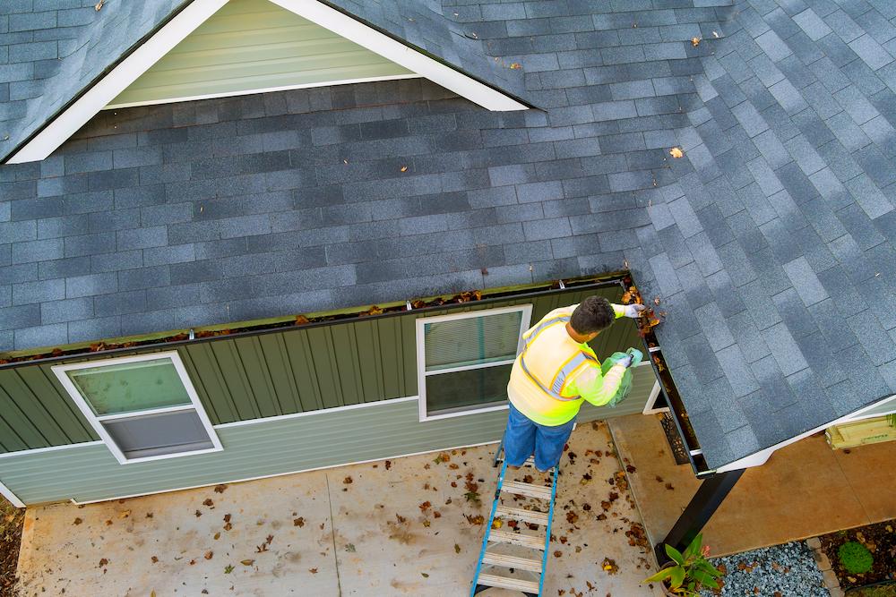 Schedule Sheridan Roof Inspections with Beard Roofing & Exteriors image shows man on ladder inspecting gutter
